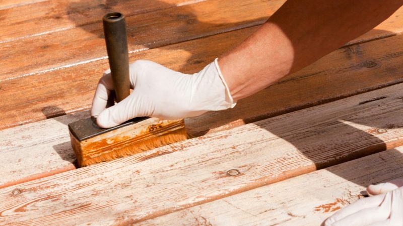 Deck maintenance apply stain on wooden decking